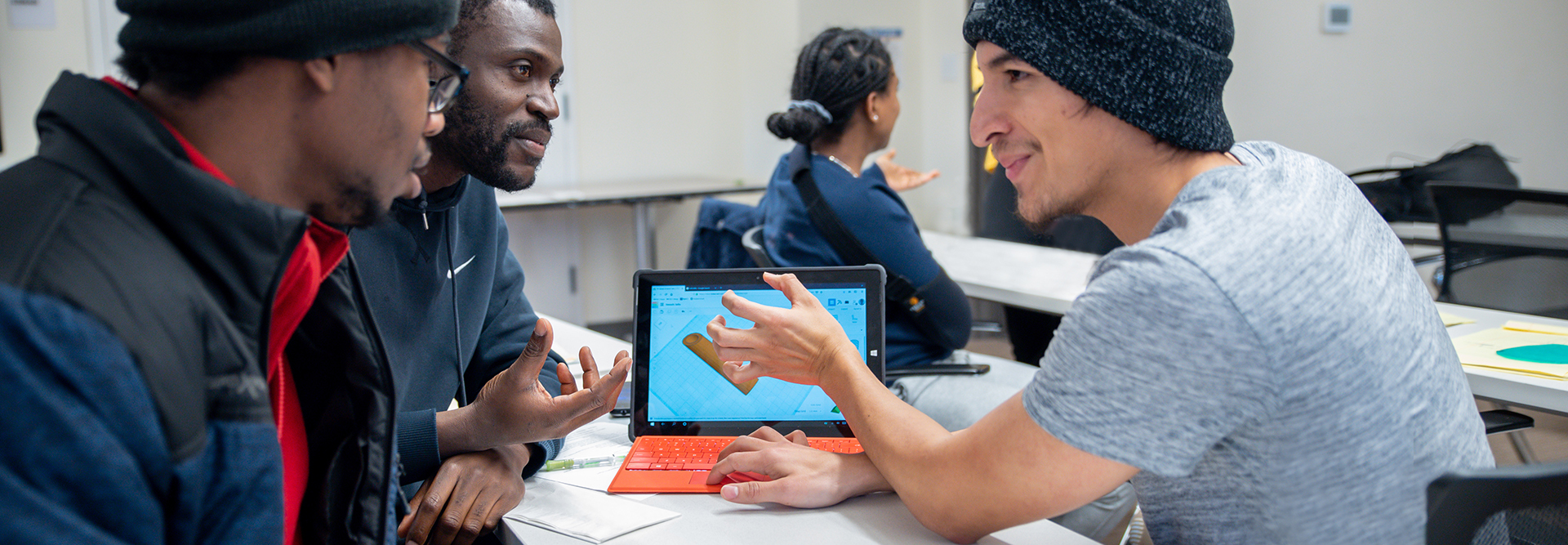Students looking at one laptop screen, smiling, and talking
